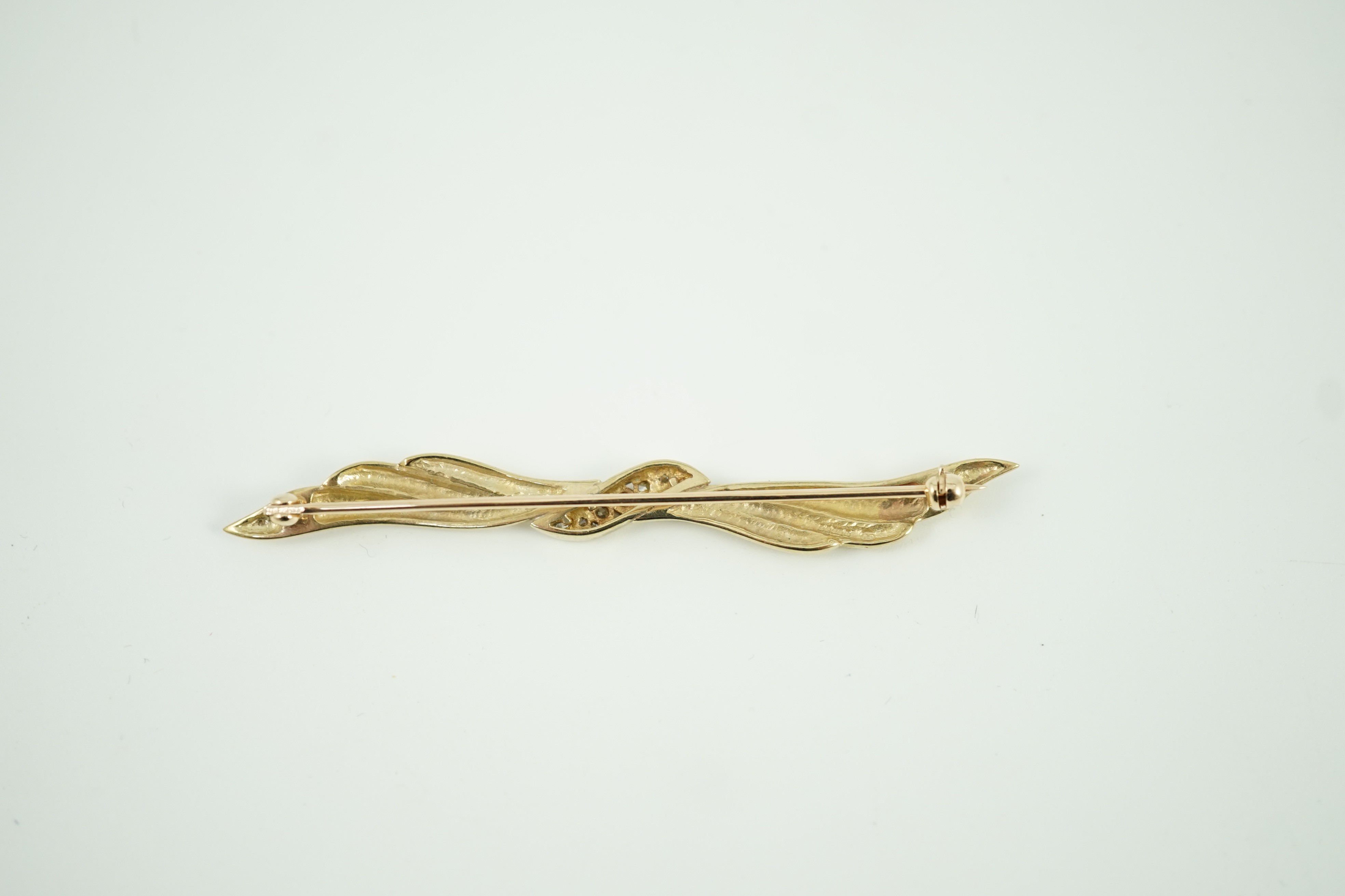 A modern 9ct gold and graduated seven stone diamond set wavy bar brooch, 68mm, gross weight 5.3 grams.